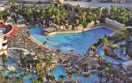 A resort with multiple swimming pools, palm trees, and a variety of lounge areas.