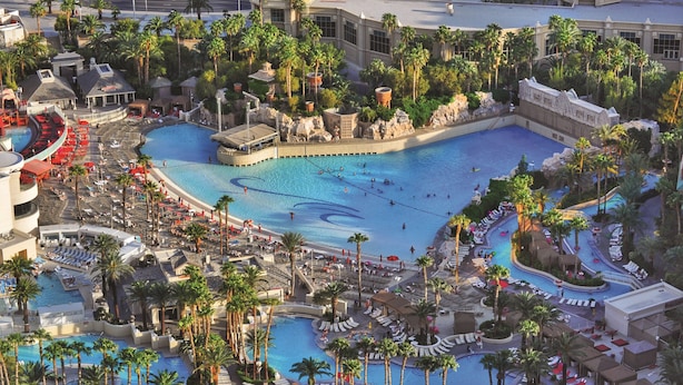 Un resort con varias piscinas, palmeras y diversas zonas de descanso.