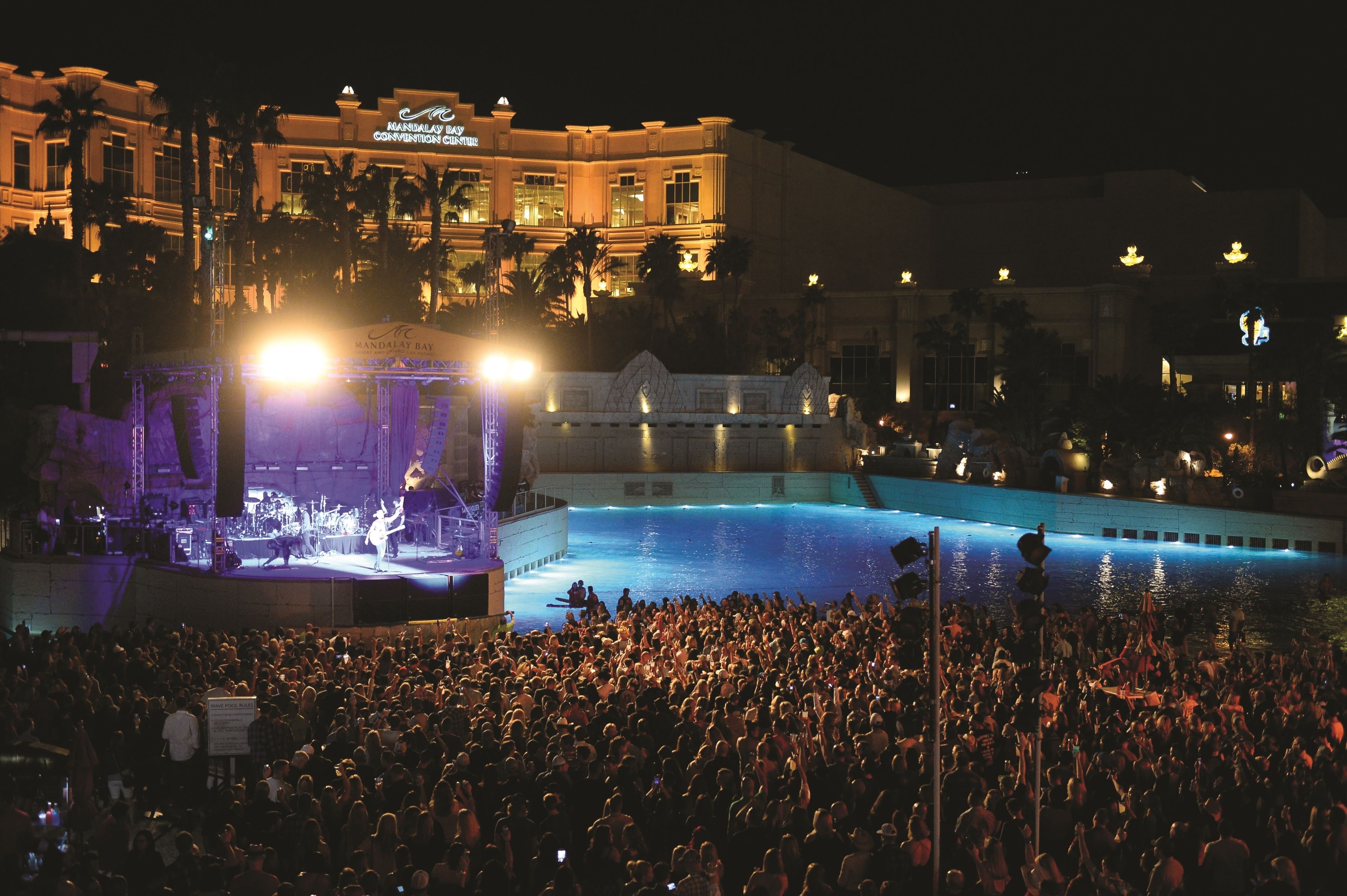 A large outdoor pool area with a stage and audience.