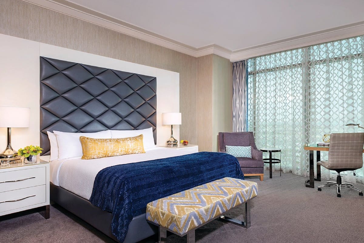 Habitación de hotel con una cama grande, un escritorio, una silla y un televisor.