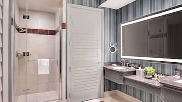 A modern bathroom with a walk-in shower, a large mirror, and a vanity with a marble countertop.