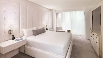 A hotel room with a large bed, a bedside table with a lamp, a chair, and a TV.