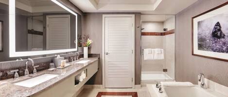 A modern bathroom with a large mirror, two sinks, a bathtub, and a shower.