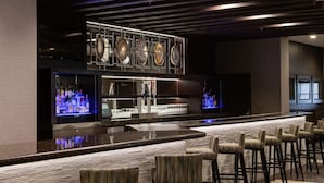 A modern bar area with a long counter, multiple seating options, and a display of decorative shells above the bar. - Embassy Suites by Hilton Las Vegas (Las Vegas)