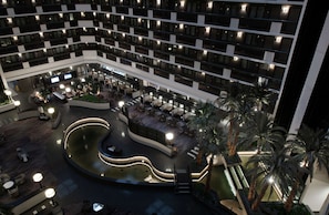 Un hotel a più piani con un cortile centrale che include una fontana, posti a sedere all'aperto e palme.