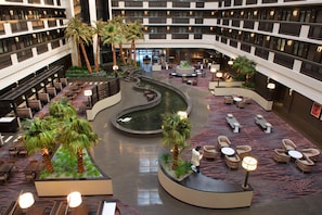 Ein geräumiger Hotel-Atrium mit mehreren Etagen, einer zentralen Wasserspiels und zahlreichen Sitzbereichen.