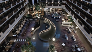 A multi-level hotel atrium with a central curved walkway, outdoor seating areas, and multiple floors with balconies. - Embassy Suites by Hilton Las Vegas (Las Vegas)