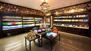 A well-lit store with shelves stocked with various snacks and beverages. There are display tables with packaged goods and a decorative light fixture on the ceiling. - Embassy Suites by Hilton Las Vegas (Las Vegas)