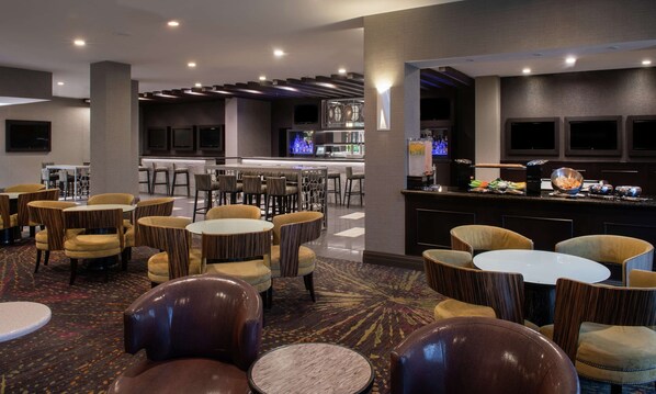 A hotel lobby with multiple seating areas, a bar, and a television screen. - Embassy Suites by Hilton Las Vegas (Las Vegas)