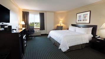 A hotel room with a bed, desk, chair, and a TV.