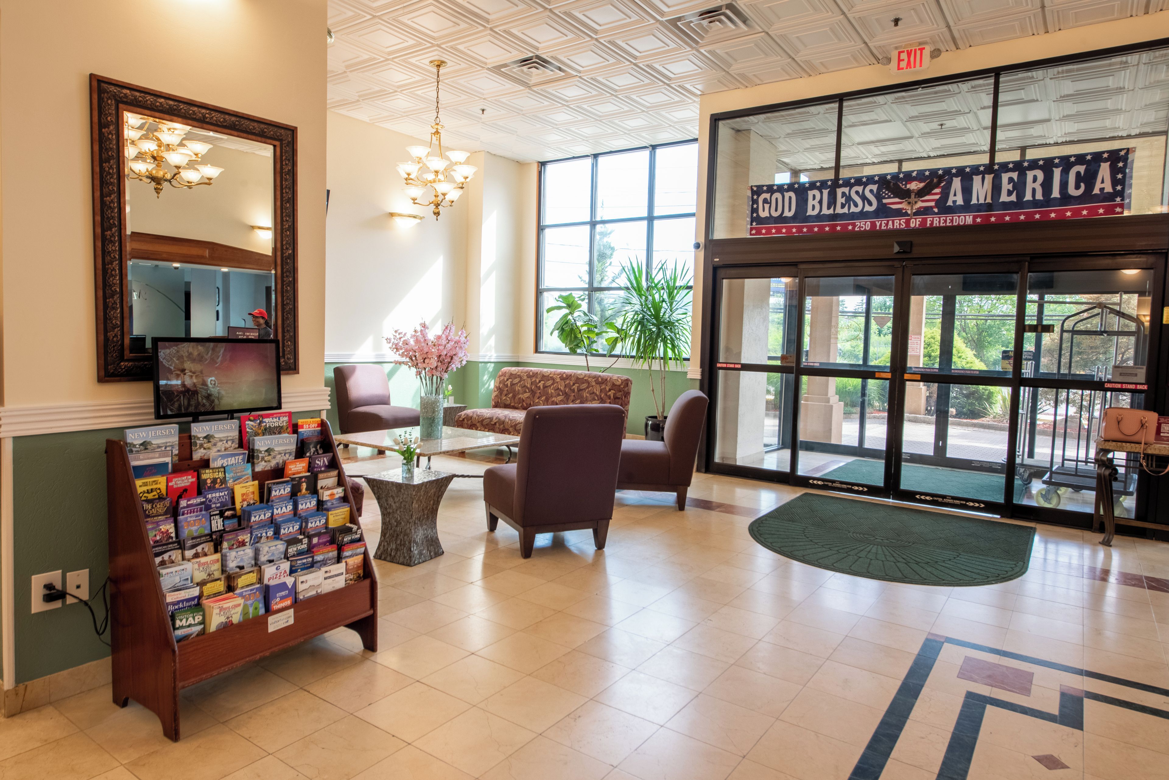 A lobby with a reception desk, seating area, and a large window with a view of greenery.