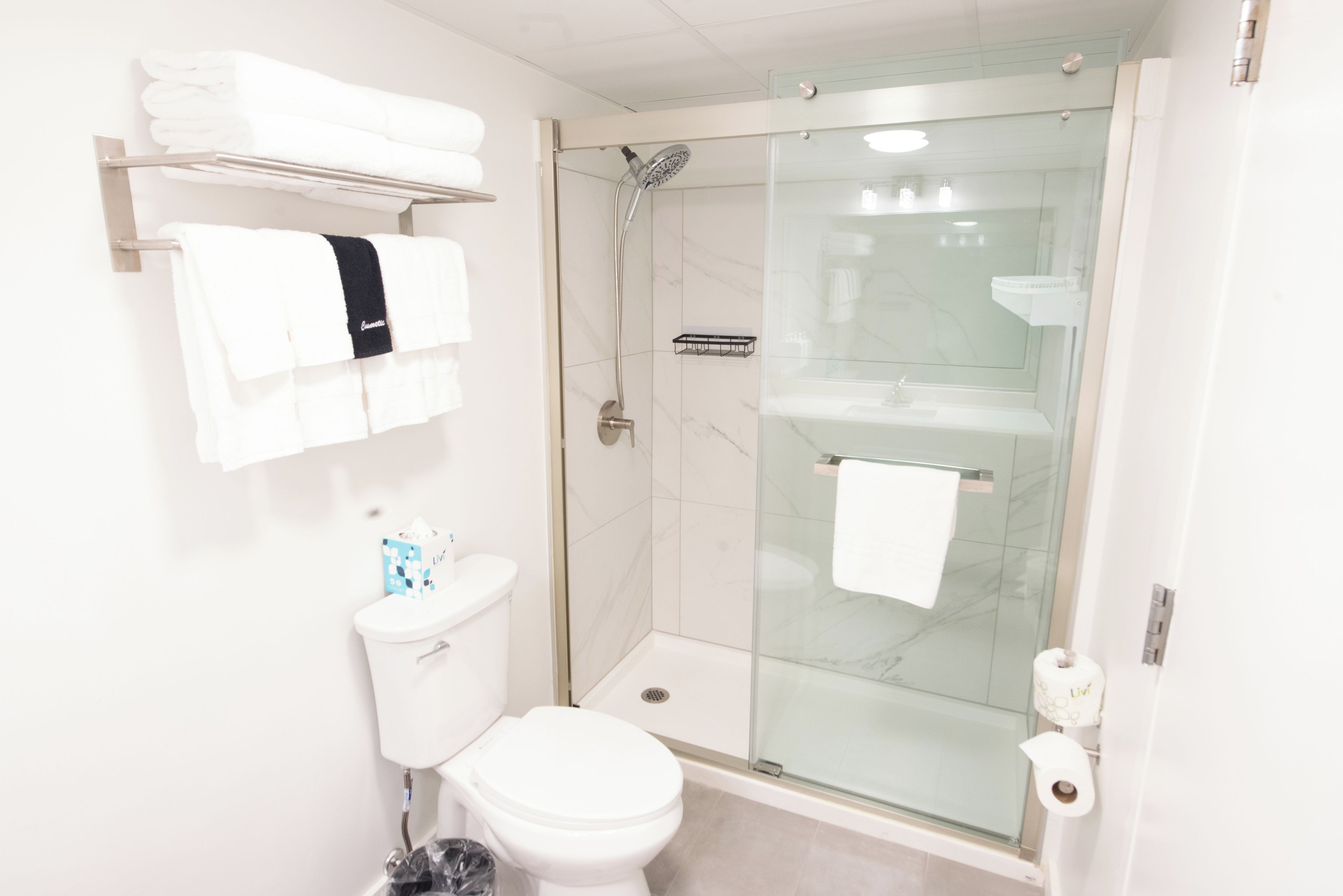A modern bathroom with a glass-enclosed shower, white fixtures, and neatly arranged towels.