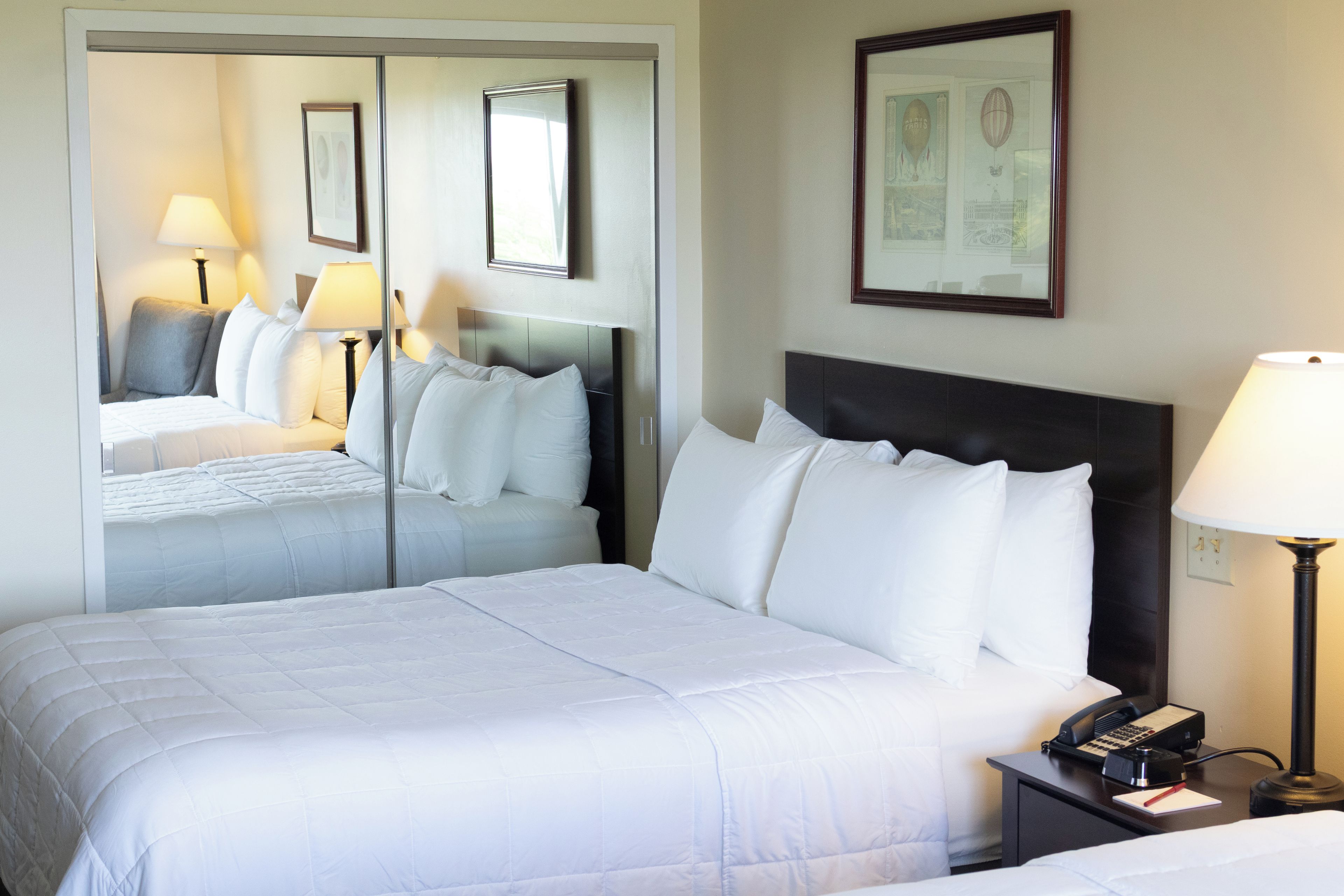 A hotel room with a large bed, a bedside table with a lamp, and a mirror on the wall.