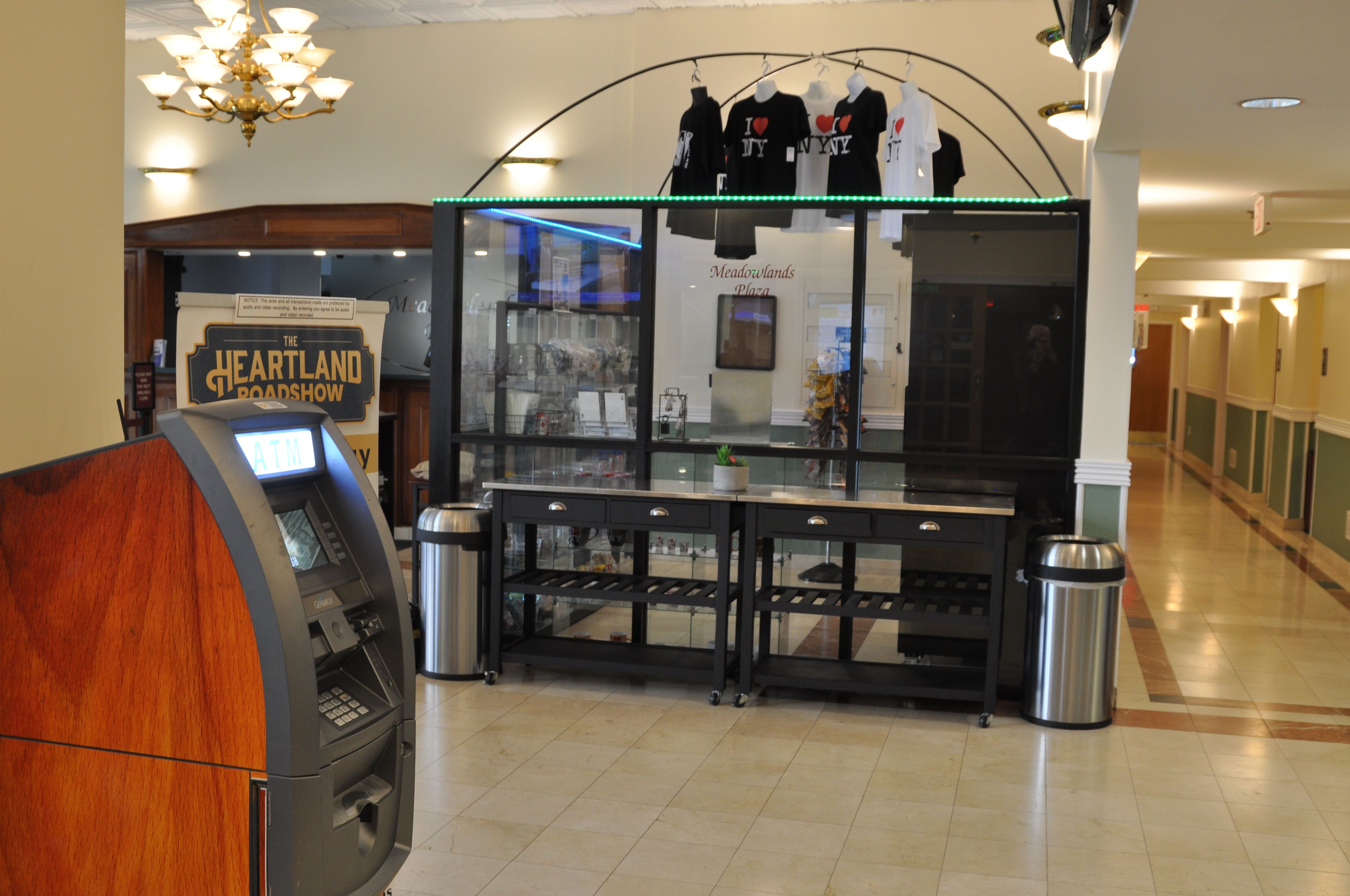 An indoor area with a cash register, a sign for 'The Heartland Roadshow,' and a display of t-shirts.