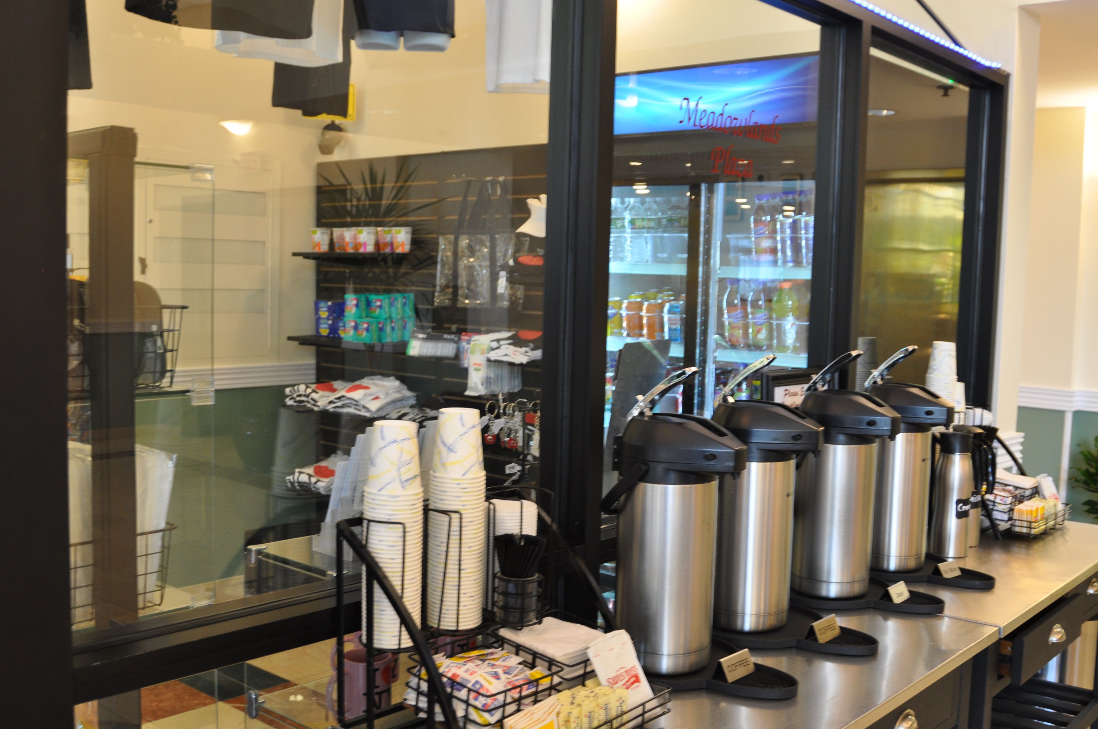 A coffee station with multiple coffee dispensers and a display of disposable cups.