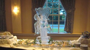 Una mesa de buffet con diversos platos, una escultura de vidrio decorativa y una ventana con cortinas.
