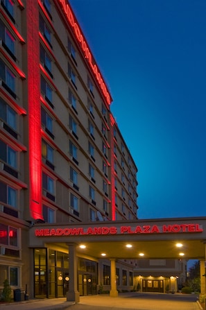 A hotel with a prominent red sign reading "MEADOWLANDS PLAZA HOTEL" and a large entrance with glass doors. - Meadowlands Plaza Hotel (Secaucus)