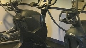 Tres bicicletas estáticas en una sala con un reloj en la pared.