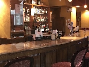 Eine Bar mit einer polierten Arbeitsplatte, Barhocker und einer Auswahl an Spirituosenflaschen.