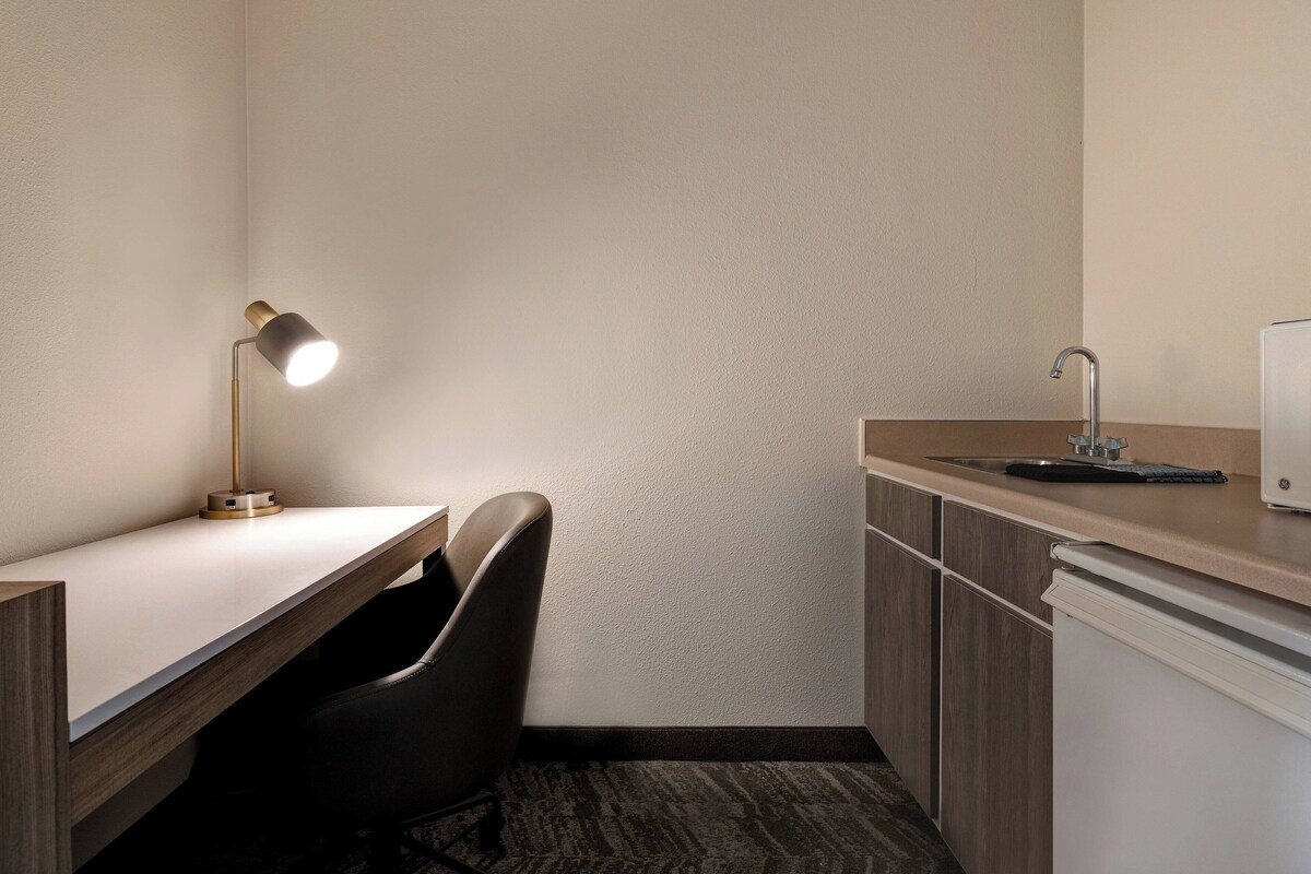A small, modern kitchenette with a white countertop, a sink, and a compact refrigerator.