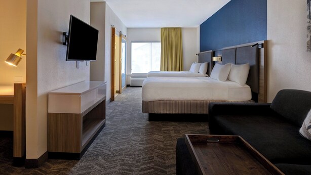 Ein Hotelzimmer mit Bett, Wandfernseher, Schreibtisch und einer Sitzecke.