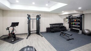 A gym with a ceiling fan, exercise equipment, and a wall-mounted rack of dumbbells. - Hampton Inn Springfield (Springfield)