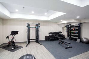 Stay fit on the go with a fully equipped home gym featuring a pull-up bar, bench press, stationary bike, and dumbbells.