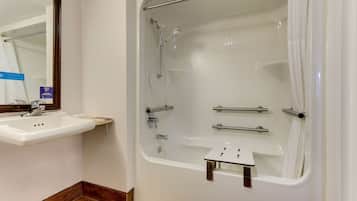 A bathroom with a white sink, a bathtub with a showerhead, and a mirror.