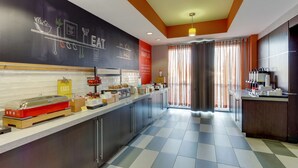 A modern kitchen with a checkered floor, a chalkboard menu, and a variety of breakfast items. - Hampton Inn Springfield (Springfield)
