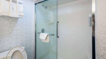 A modern bathroom with a glass-enclosed shower, a toilet, and a towel rack.