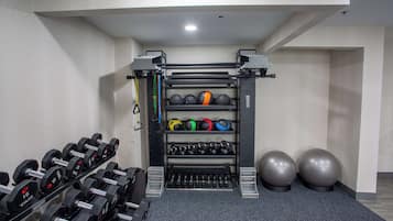 Uma academia com equipamentos de musculação, bolas de exercício e halteres.