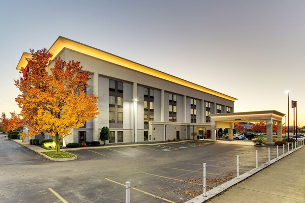 Stylish building with a flat roof and grid-patterned windows, set amidst a spacious parking lot.