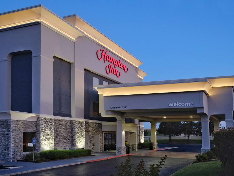 A Hampton Inn building with a stone facade, a 'Welcome' sign, and a 'Clearance 12'6' sign.