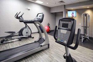 Un gimnasio con cintas de correr, una bicicleta estática y una máquina de remo.