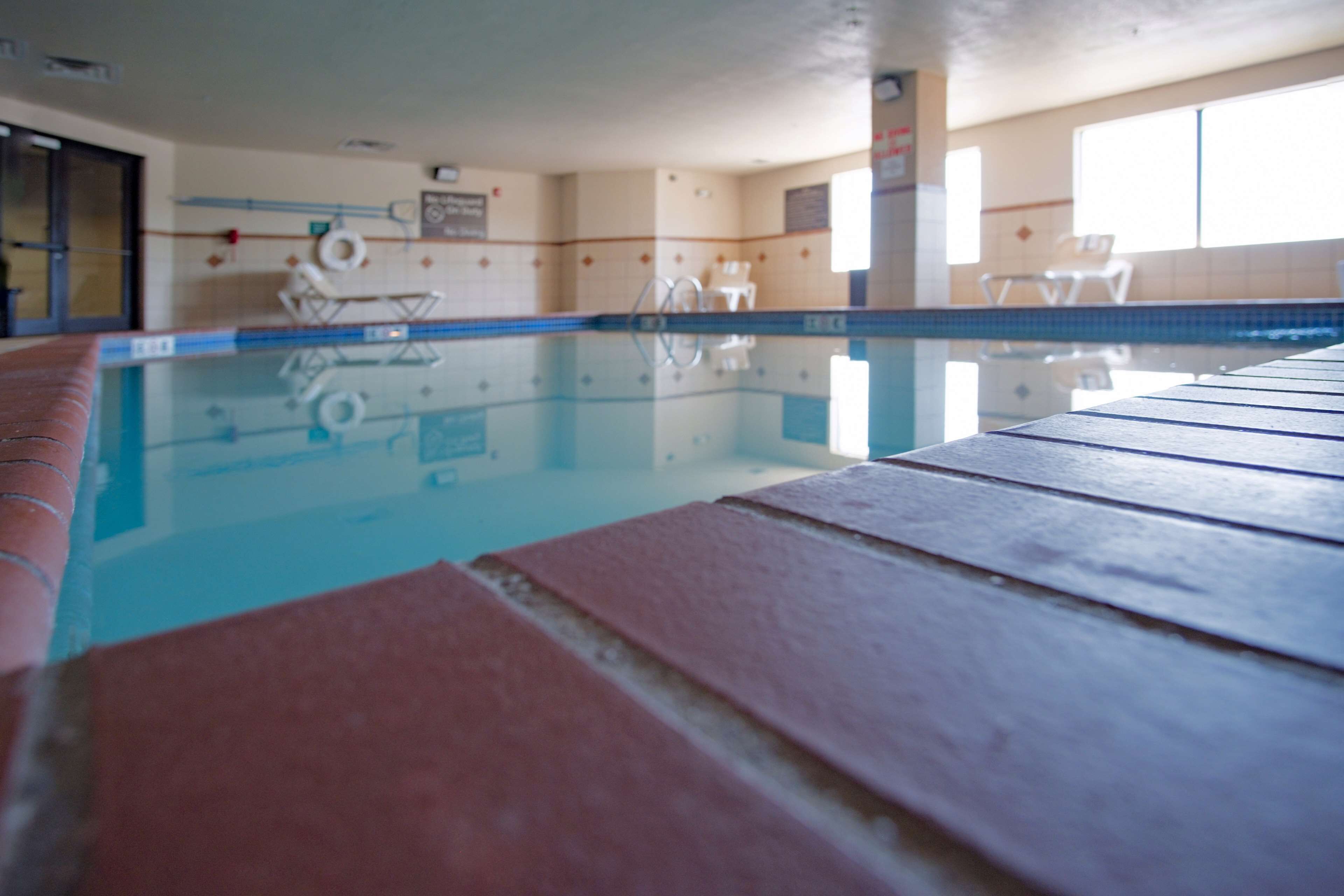 Una piscina interior amb aigua cristal·lina, parets revestides de rajoles i algunes gandules.