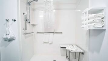 A modern bathroom with a shower, a toilet, and a sink. There are towels and a bag hanging on the wall.