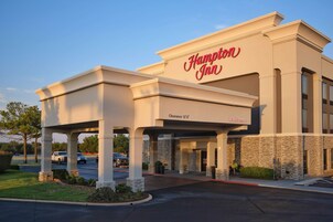 Un Hampton Inn con una entrada despejada, un cartel que indica 3,6 metros de altura libre y un letrero acogedor.