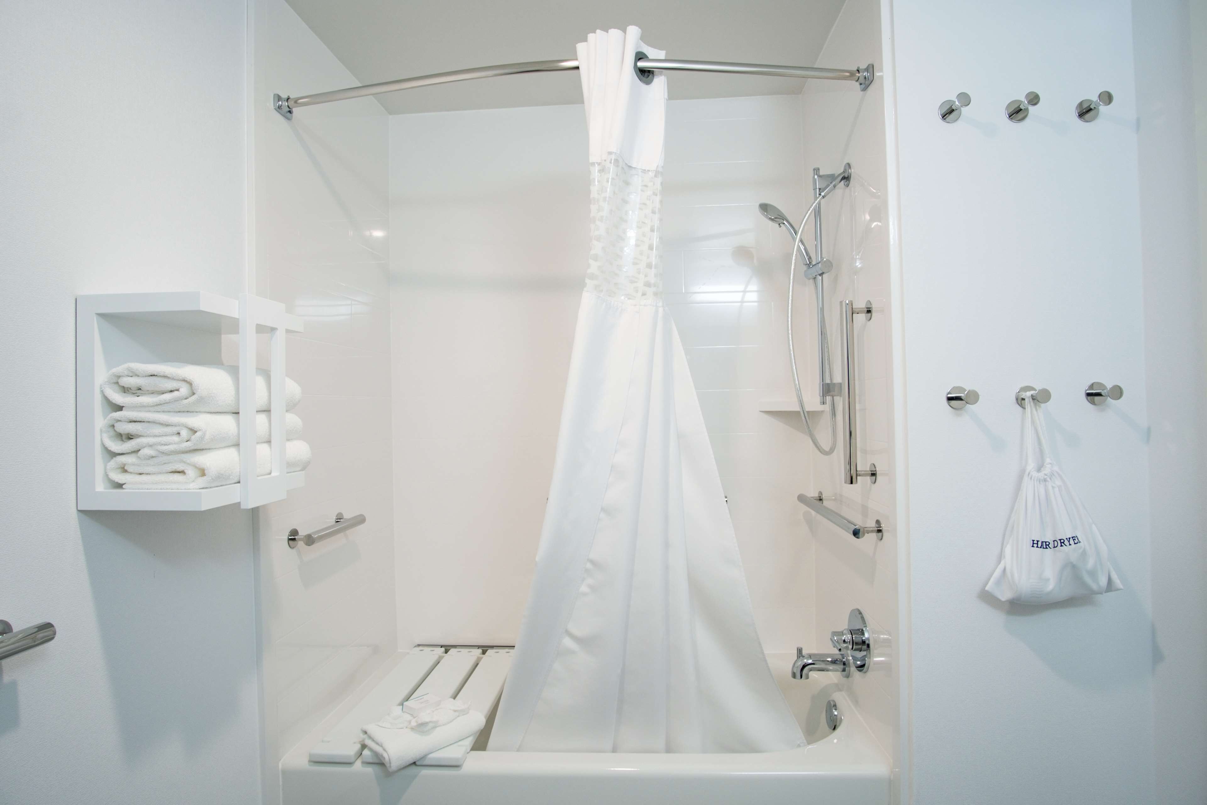 Un baño moderno con cabina de ducha de vidrio, un toallero blanco y un cabezal de ducha.