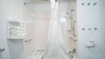 Un baño moderno con cabina de ducha de vidrio, un toallero blanco y un cabezal de ducha.