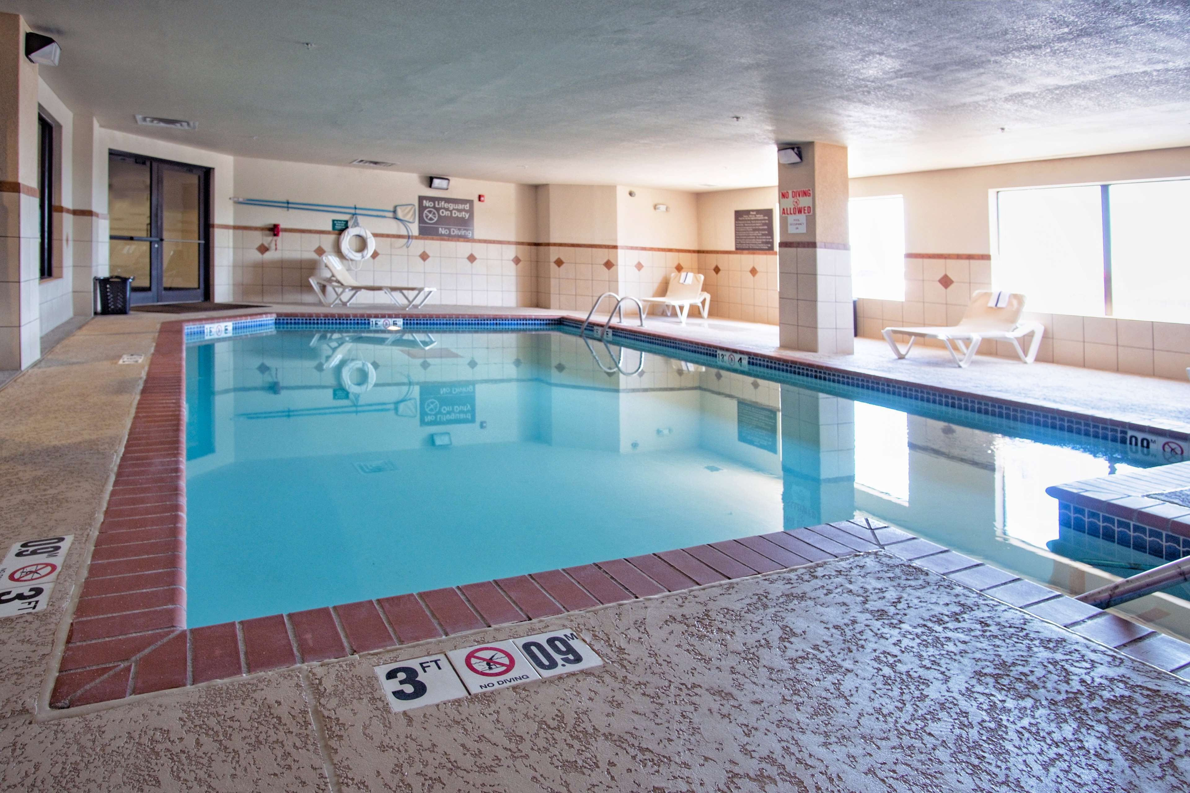 Una piscina interior con agua cristalina, un indicador de profundidad de 0.9 metros y sillones de descanso a lo largo de la piscina.