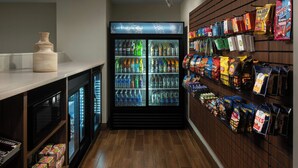A vending area with a refrigerator stocked with beverages and snack bags.
