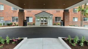 A brick building with a covered entrance, a clear pathway, and flower beds.