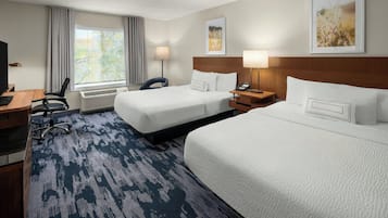 A hotel room with two beds, a desk, a chair, a TV, and a window with curtains.