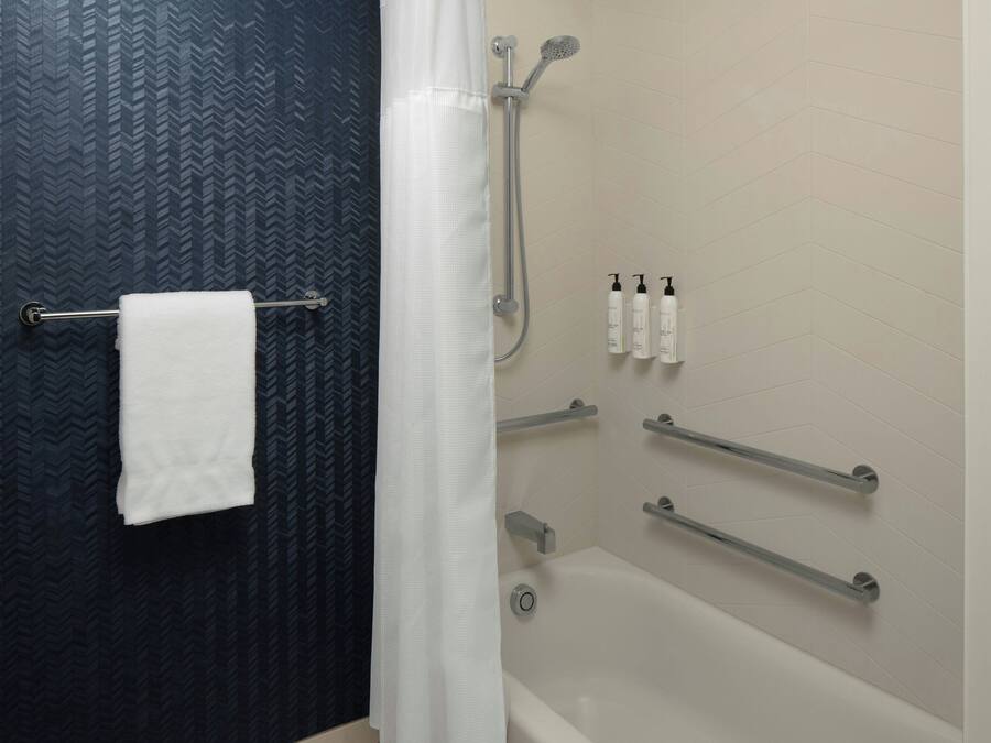 A bathroom with a shower, a towel rack, and toiletries on the wall.