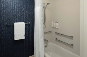 Un baño con ducha, toallero y artículos de aseo en la pared.