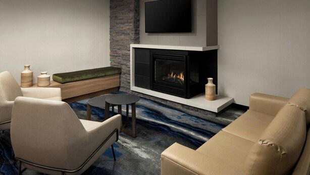 A modern living room with a fireplace, comfortable seating, and a flat-screen TV mounted above the fireplace.