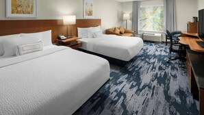 A hotel room with two beds, a desk, a chair, a TV, and a window with curtains.