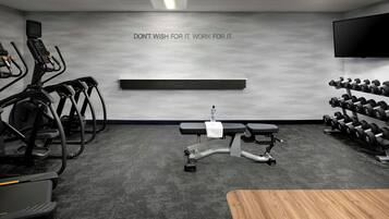 A modern gym with treadmills, a bench press, and dumbbells.