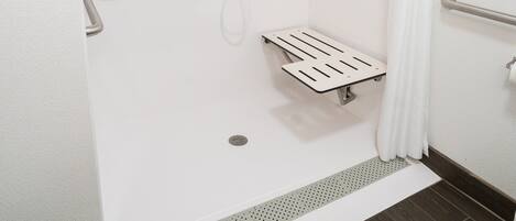 A walk-in shower with a grab bar, a showerhead, and a handheld shower attachment.