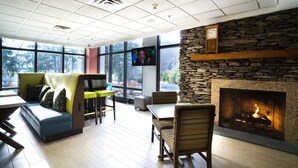 A modern interior with a stone fireplace, seating areas, and a television screen. - Hampton Inn Clarks Summit (Clarks Summit)